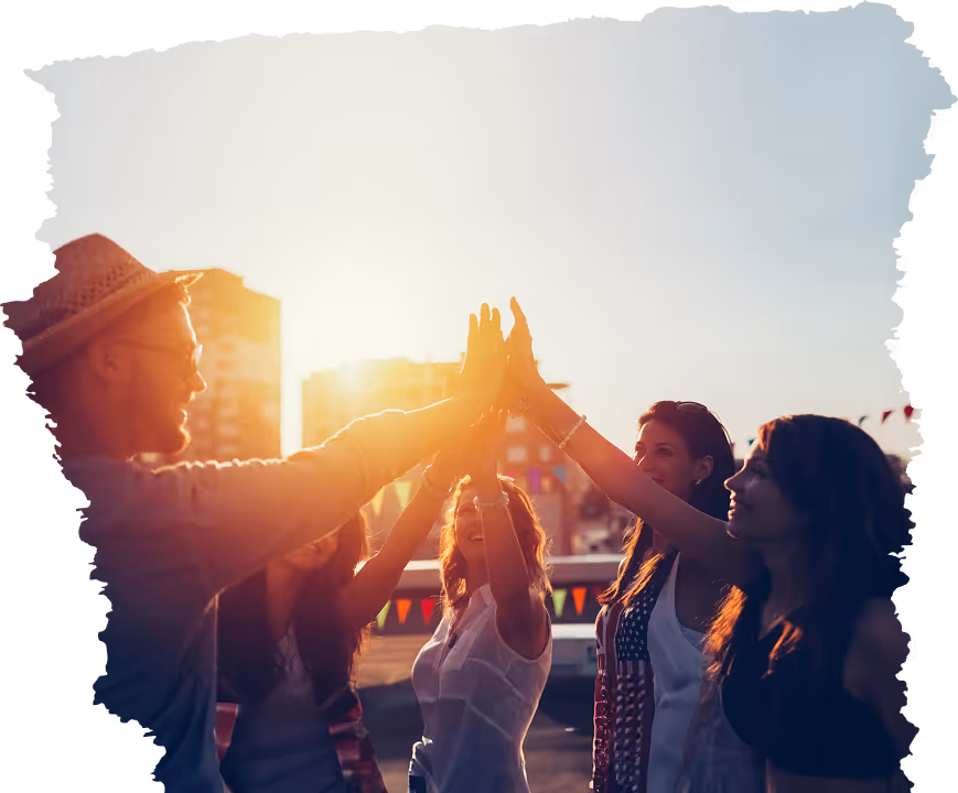 Groupe de personnes donnant un high-five collectif au coucher du soleil en extérieur.