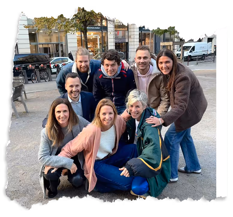 Un groupe de huit personnes souriantes posant ensemble dans un espace urbain en plein air.