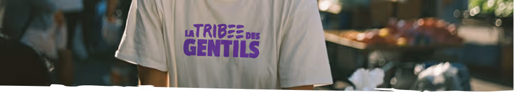 Personne portant un t-shirt blanc avec le texte violet « La Tribu des Gentils » au centre.