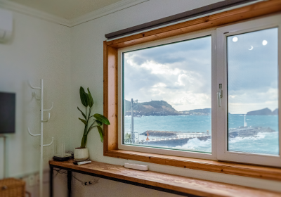 '제주늘보의오후' 패밀리룸 객실 창에서 보이는 하늘 바다 그리고 섬.
The sky, the sea, and the island from the family room window of 'JEJUNEULBO'