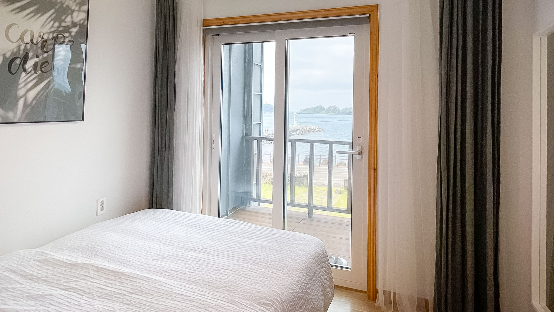 '제주늘보의오후' 패밀리룸 다른 객실 창에서 본 바다의 모습. 'JEJUNEULBO' Family Room The view of the sea from the other room window.