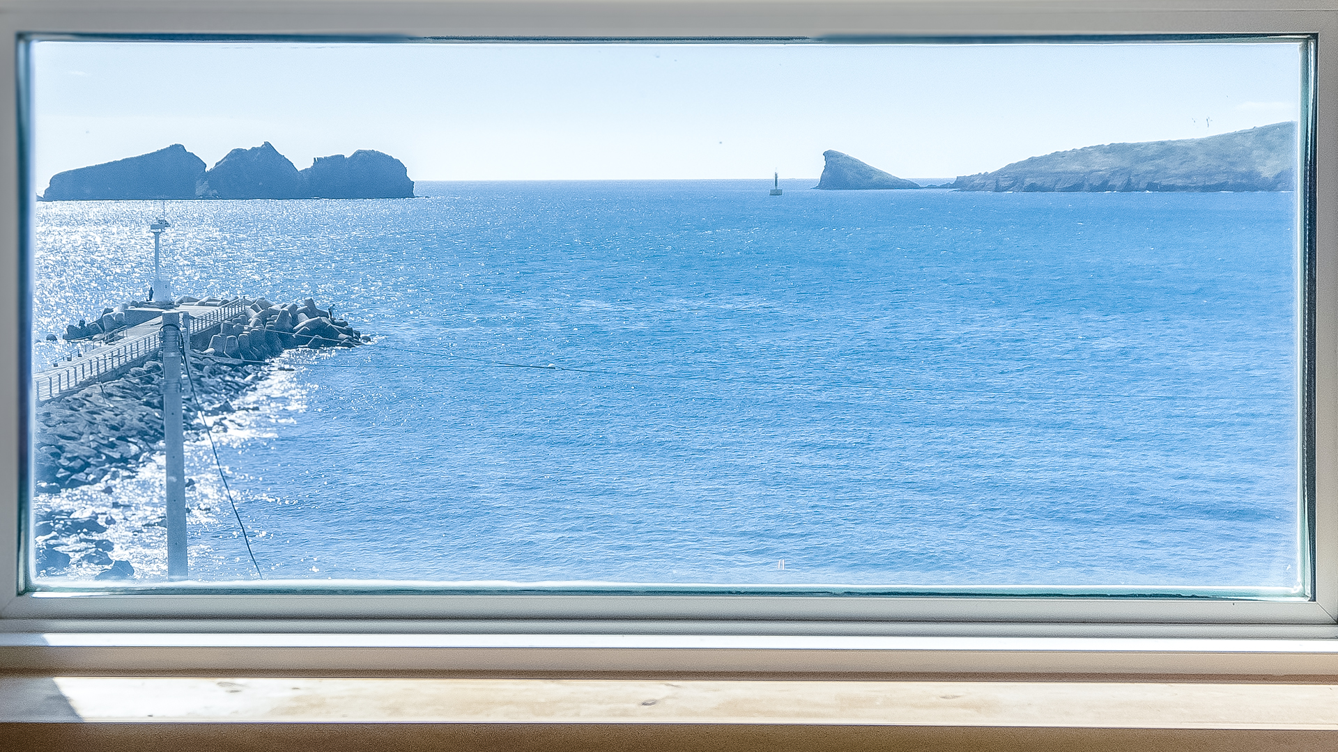 '제주늘보의오후' 2층 듀플렉스룸 창문에서 보이는 용수항과 해안의 풍경에 차귀도가 있는 장면.
'JEJUNEULBO' is a scene with Cha Guido Island in the Yongsu Port and coastal scenery seen from the duplex room window on the second floor.