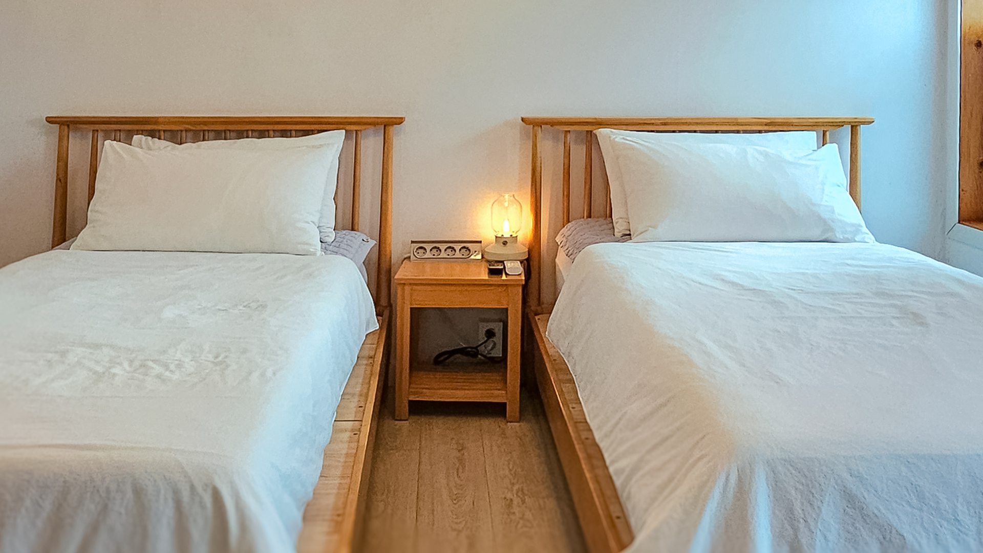 '제주늘보의오후' 1층 트윈룸에 배치된 침대 이미지. An image of a bed placed in a twin room on the first floor of 'JEJUNEULBO'.