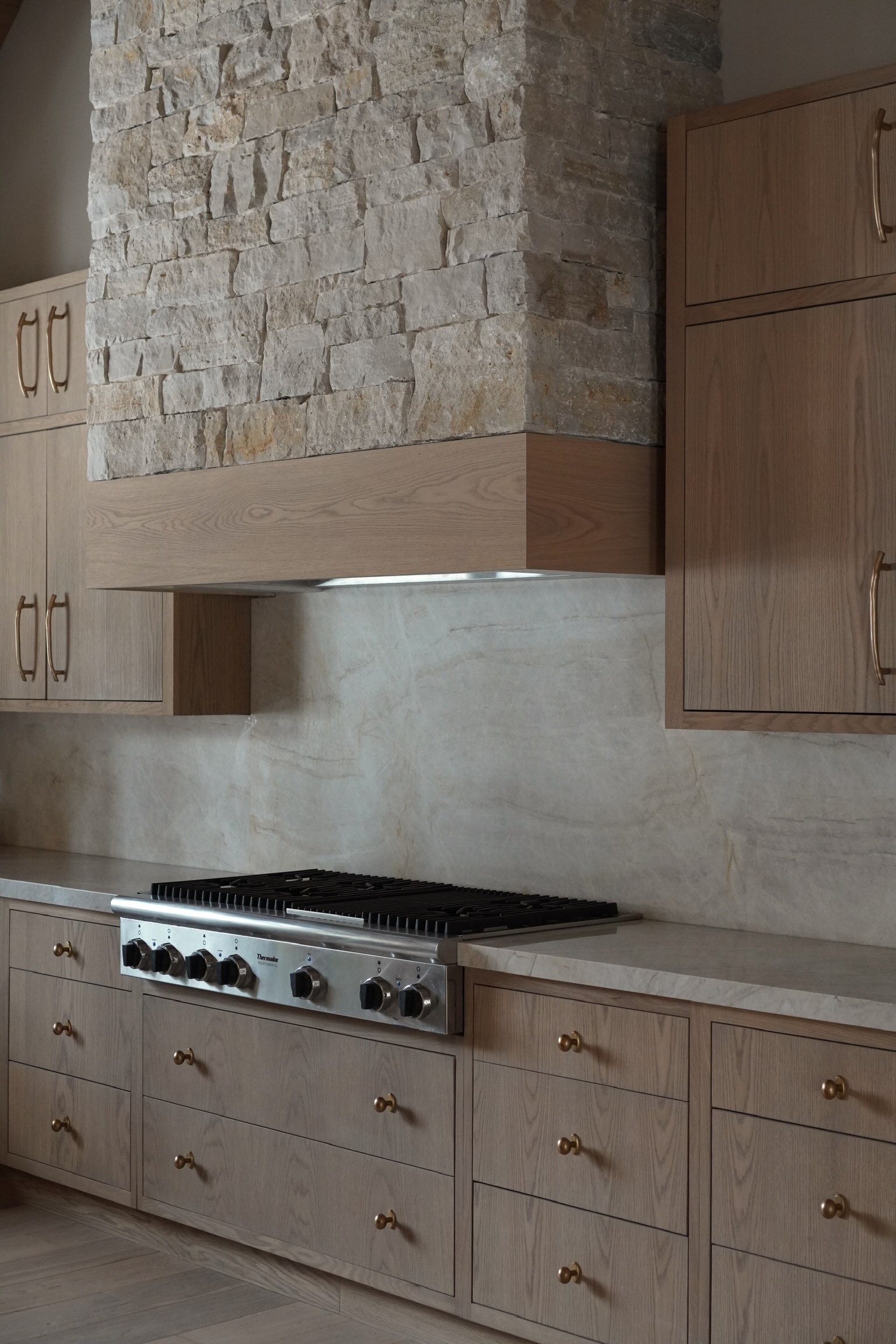 Custom white oak kitchen cabinetry with stone range hood and marble backsplash, Eské Studio project