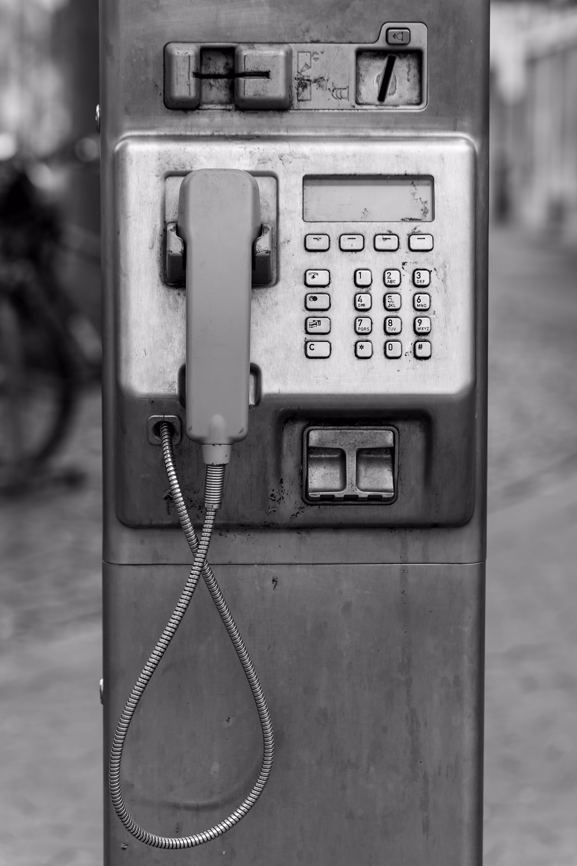 Vintage public payphone with a hanging receiver, symbolizing connection and communication.