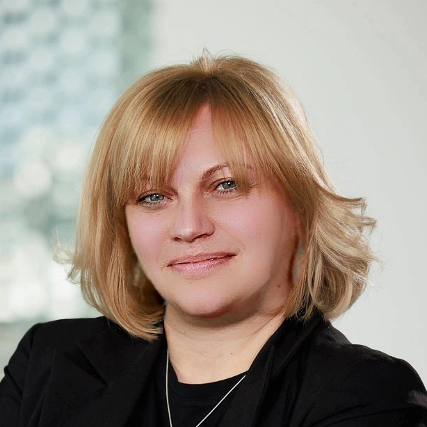 Portrait photograph of a woman with long hair, smiling.
