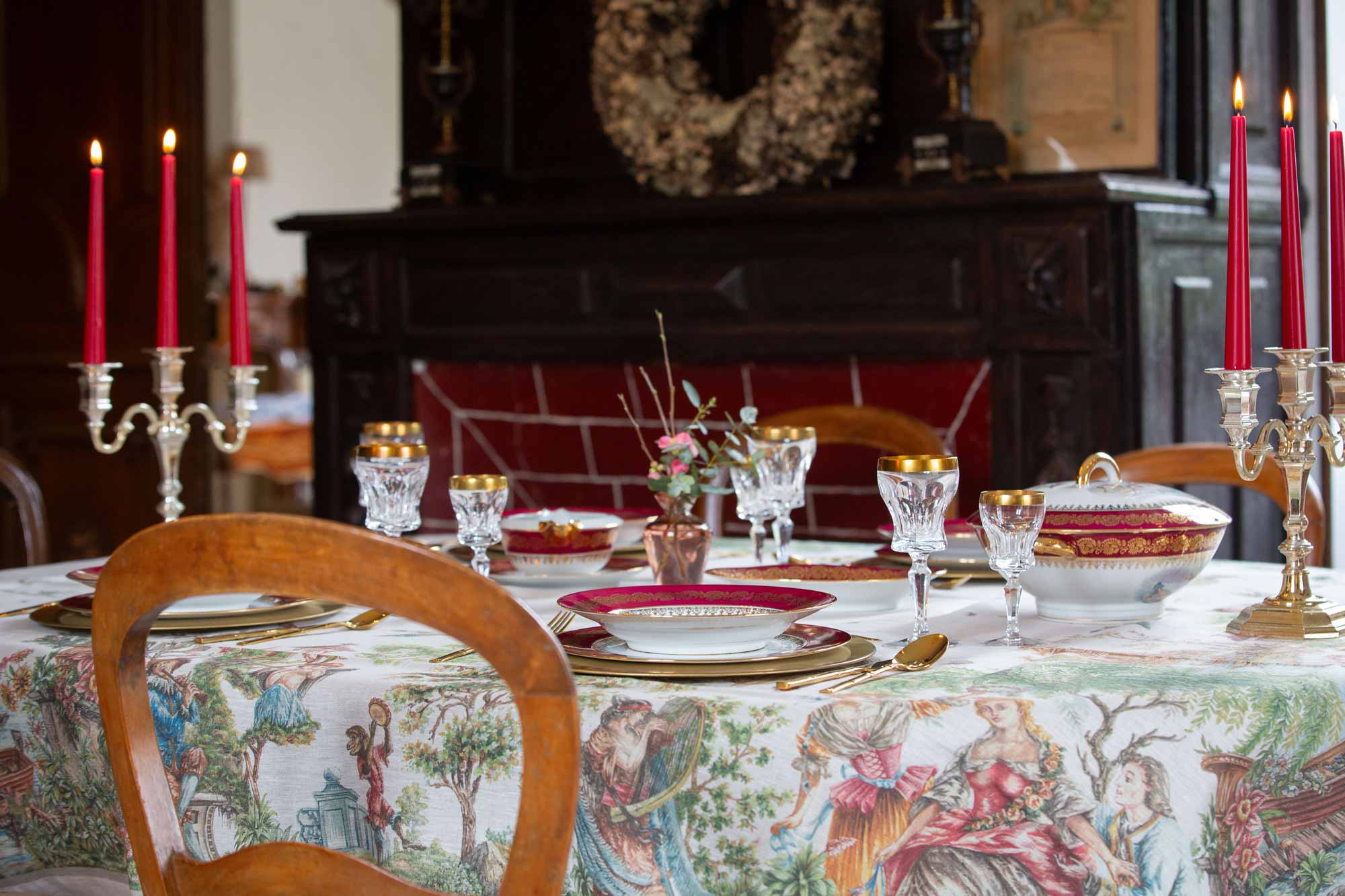 Statue eines Musketiers mit breitkrempigem Hut, Mantel und Schwert vor einer steinernen Balustrade und Bäumen bei klarem Himmel.