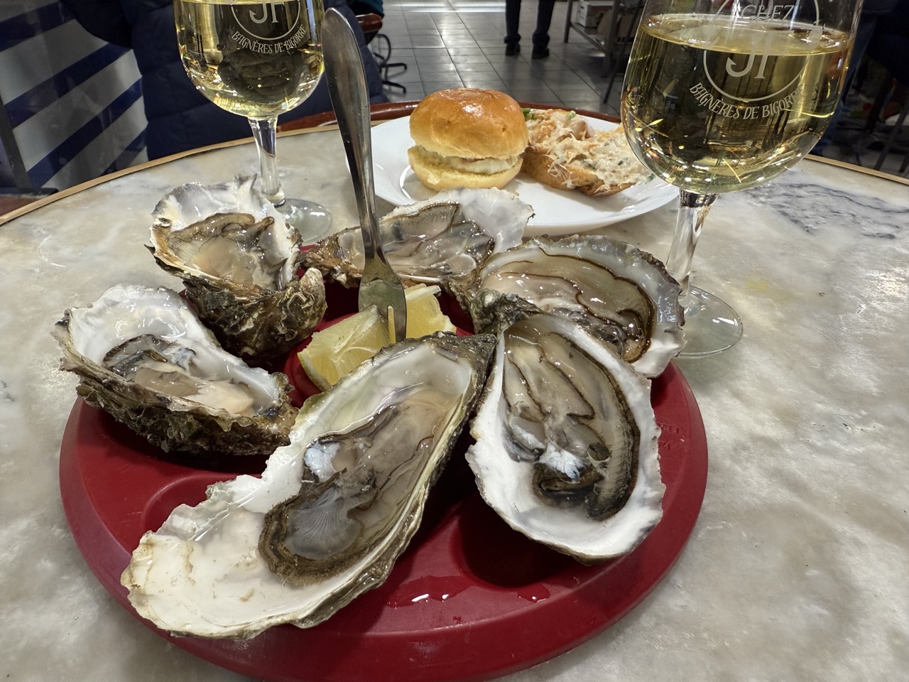 Blick nach oben auf einen Innenhof mit historischem steinernem Treppenaufgang und Fachwerkgebäude mit geöffneten Holzläden.