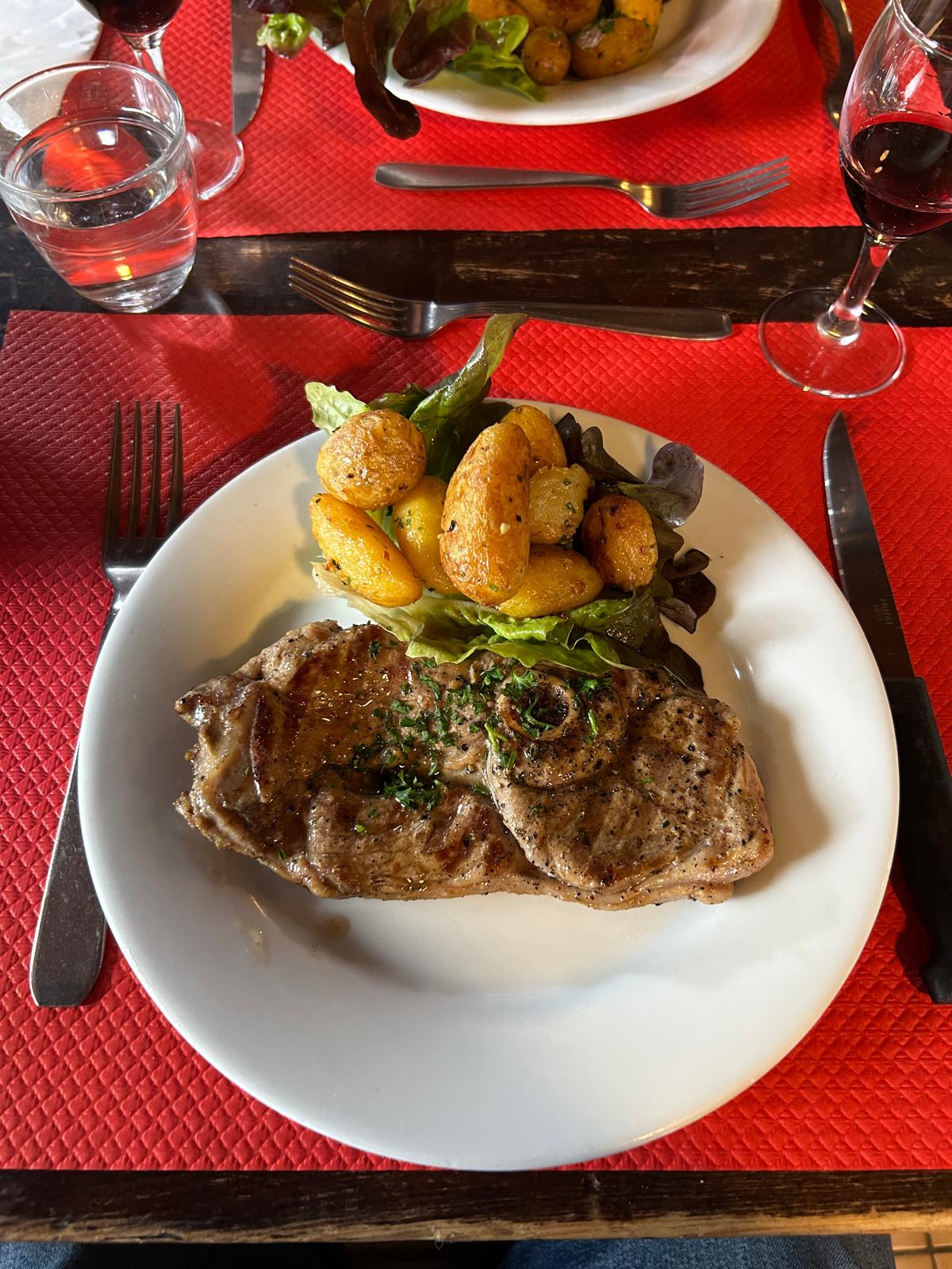 Blick nach oben auf einen Innenhof mit historischem steinernem Treppenaufgang und Fachwerkgebäude mit geöffneten Holzläden.