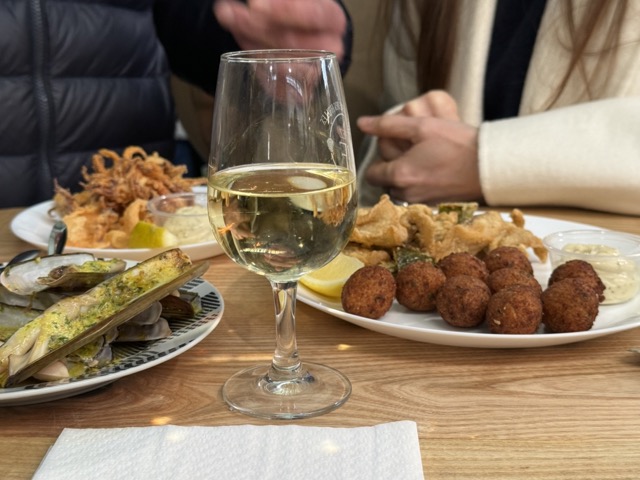 Verre de vin blanc à côté d'une assiette bleue avec des huîtres fraîches sur glace et une tranche de citron.