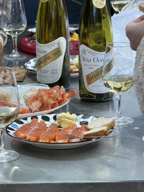 Verre de vin blanc à côté d'une assiette bleue avec des huîtres fraîches sur glace et une tranche de citron.