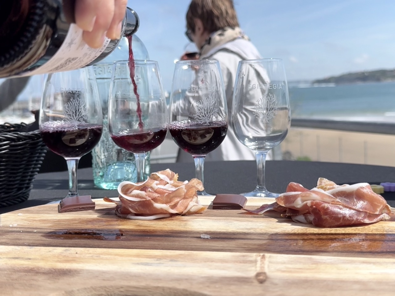 Glas Weißwein neben einem blauen Teller mit frischen Austern auf Eis und einer Zitronenscheibe.