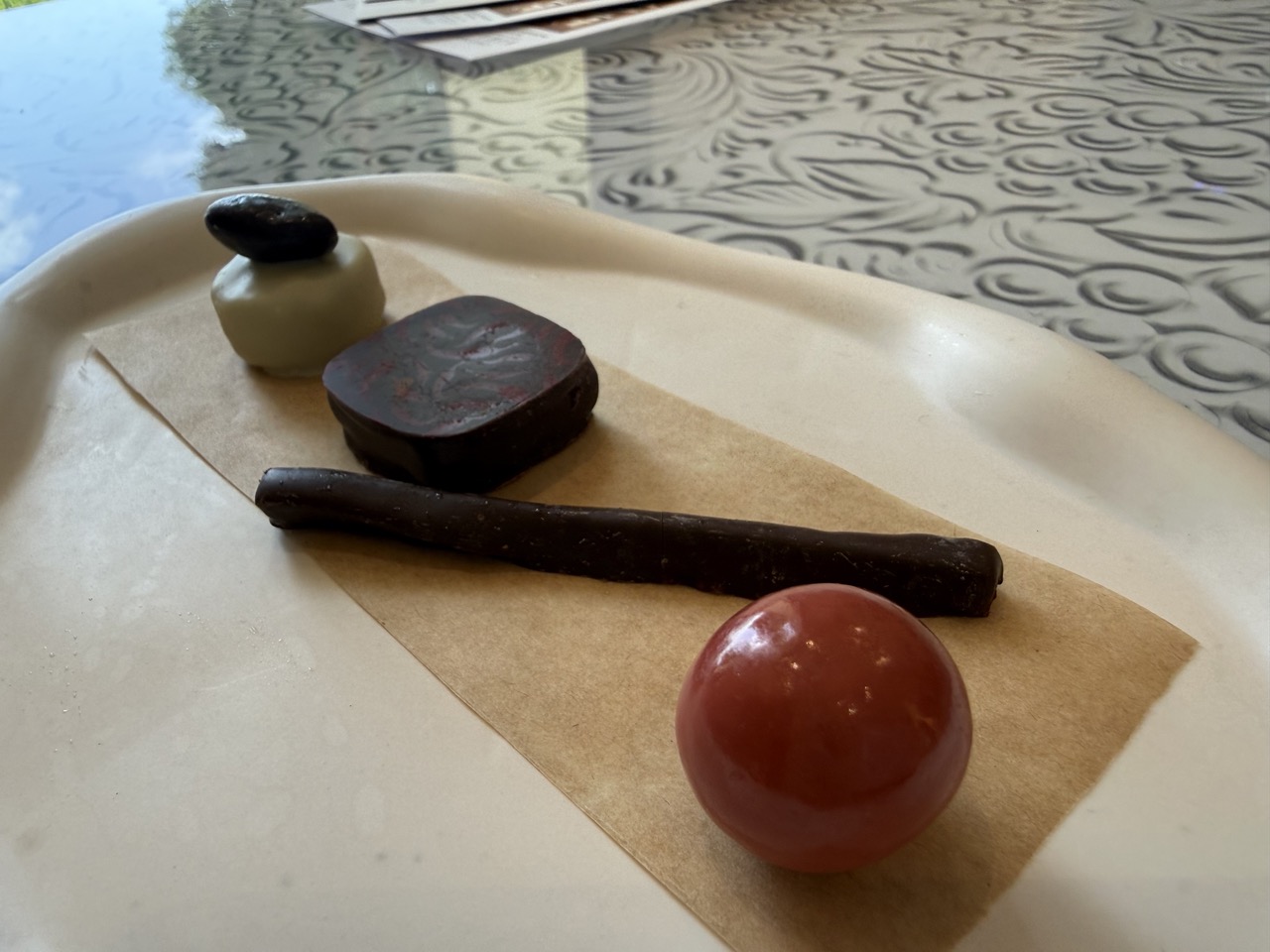 Crème brûlée in einem Einmachglas mit Sternfrucht, Himbeere, Erdbeere und roten Johannisbeeren auf einem weißen Teller mit einem Löffel daneben.