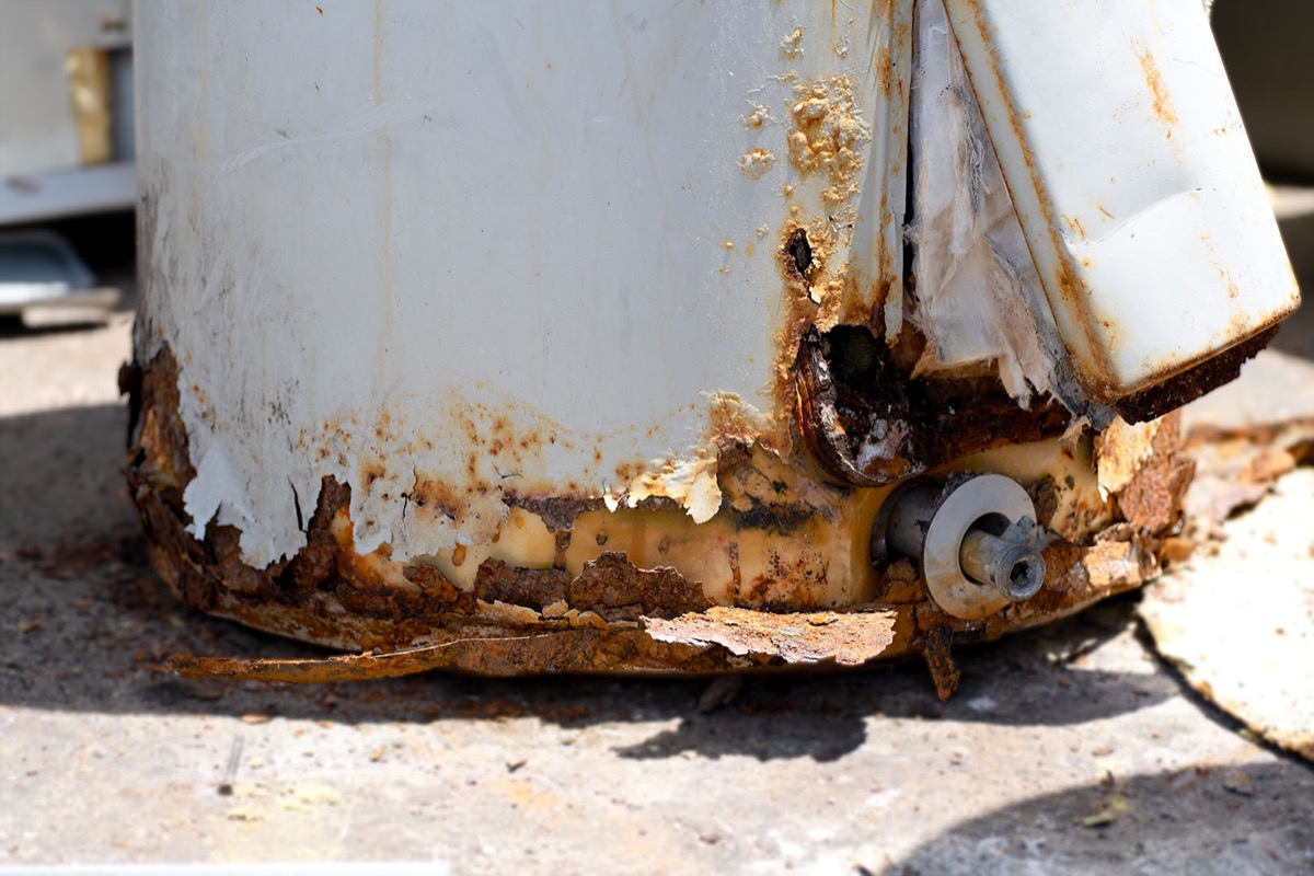 Base of an old water heater tank rusted through and flaking