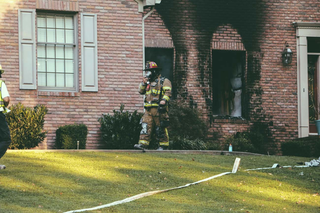 firefighter in front of burnt home