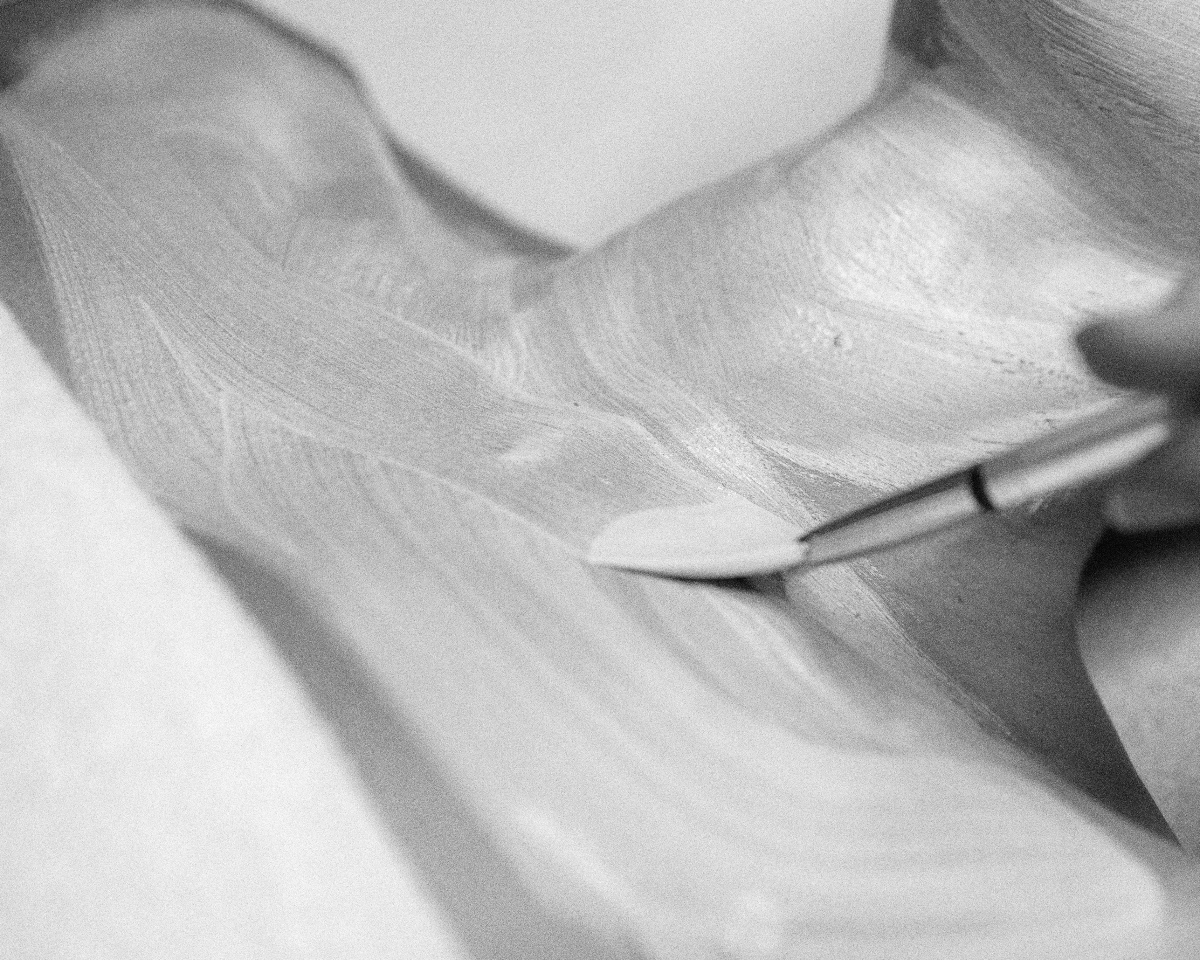 Close-up of a hand applying a white cream with a small spatula on shoulder skin.