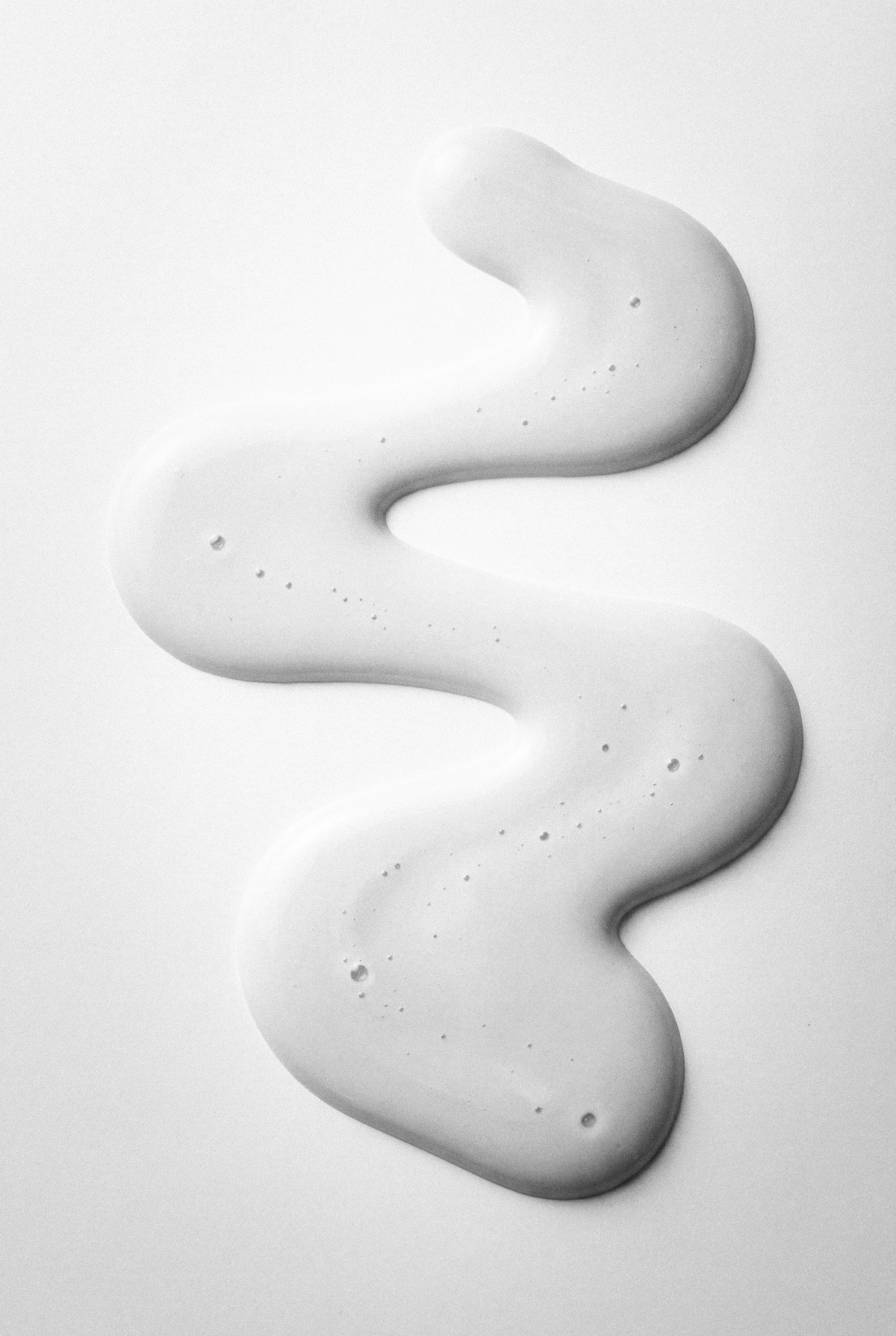 Abstract white cream or lotion swirled in a wavy pattern on a white surface.