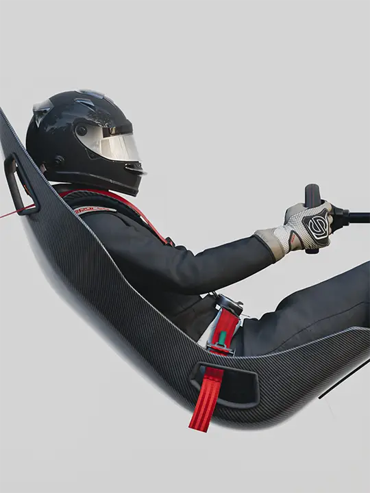 A race car driver sitting in a floating seat in a white studio environment