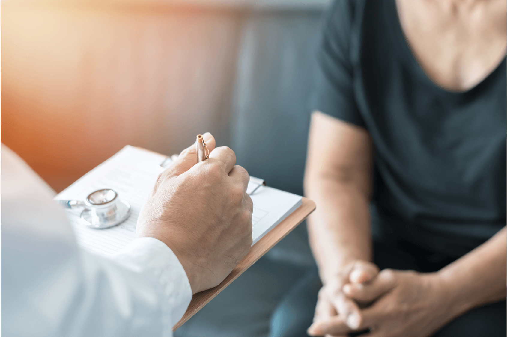 A healthcare professional notes patient information during a consultation about chronic care.