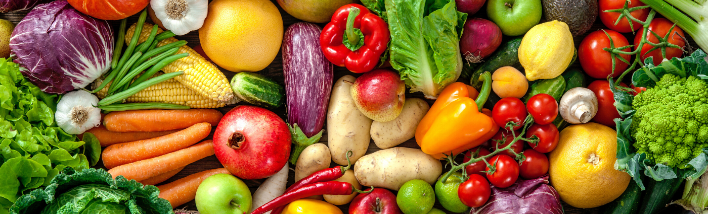 An assortment of colorful vegetables and fruits, including greens, peppers, and apples.