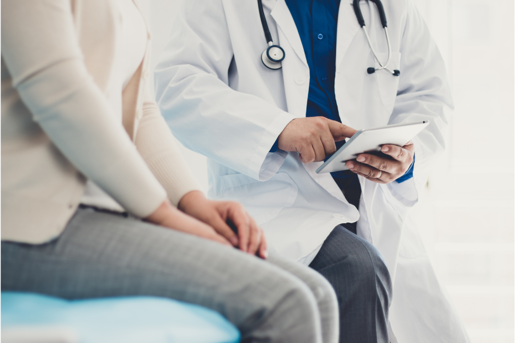 A medical professional using a tablet while consulting with a patient.