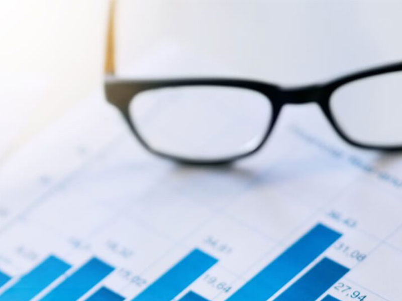 Glasses resting on a graph chart displaying increasing bar data points.
