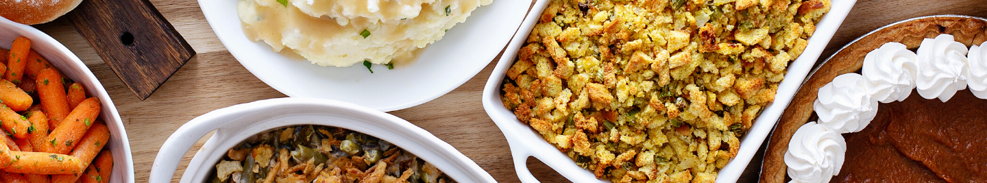 A spread of healthy Thanksgiving dishes including mashed potatoes, stuffing, glazed carrots, and