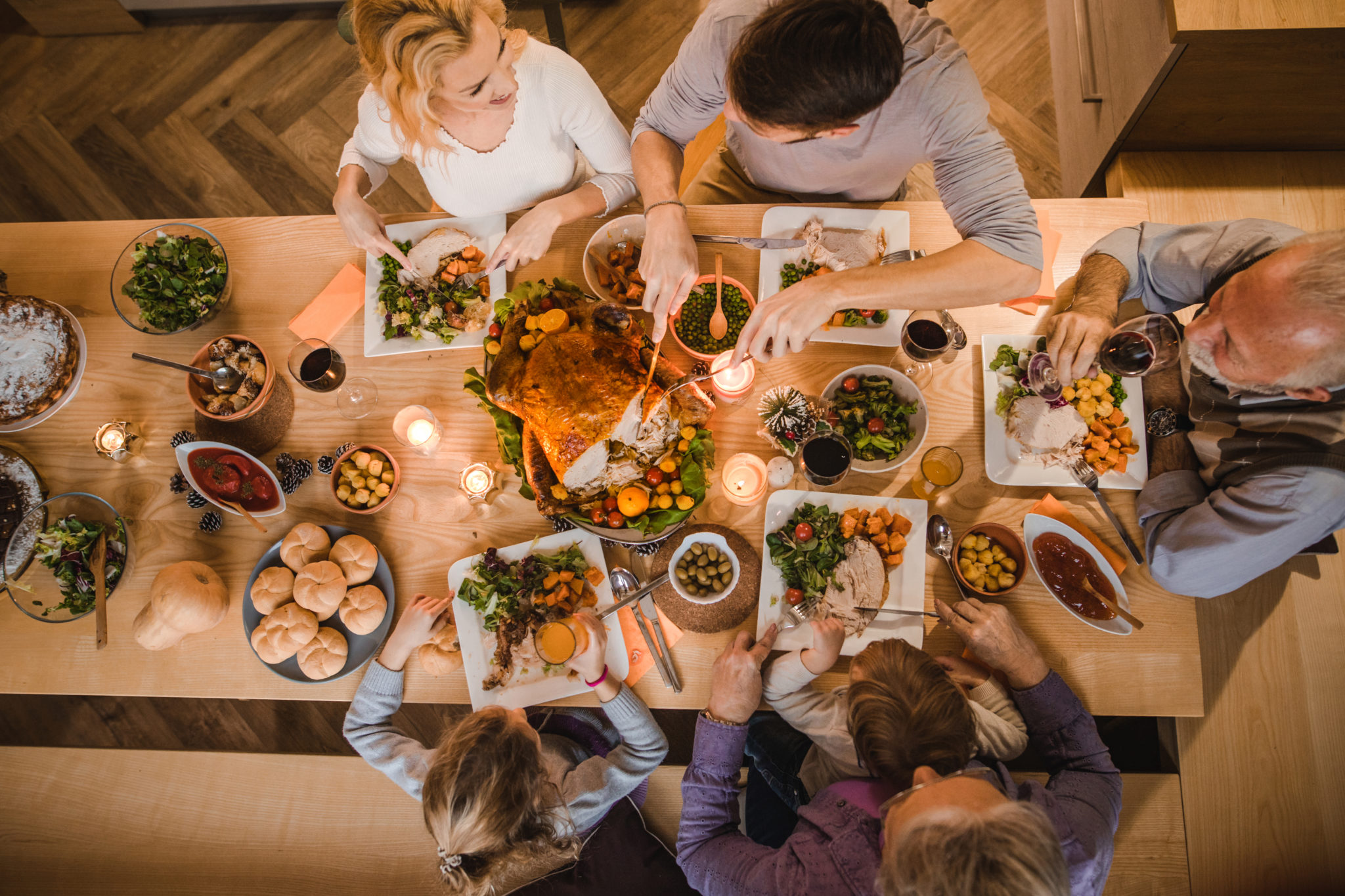 A festive holiday dinner with people enjoying turkey, vegetables, and salads at a large table.
