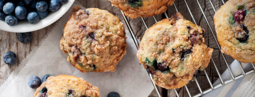 Freshly baked blueberry muffins cooling on a wire rack, surrounded by fresh blueberries.