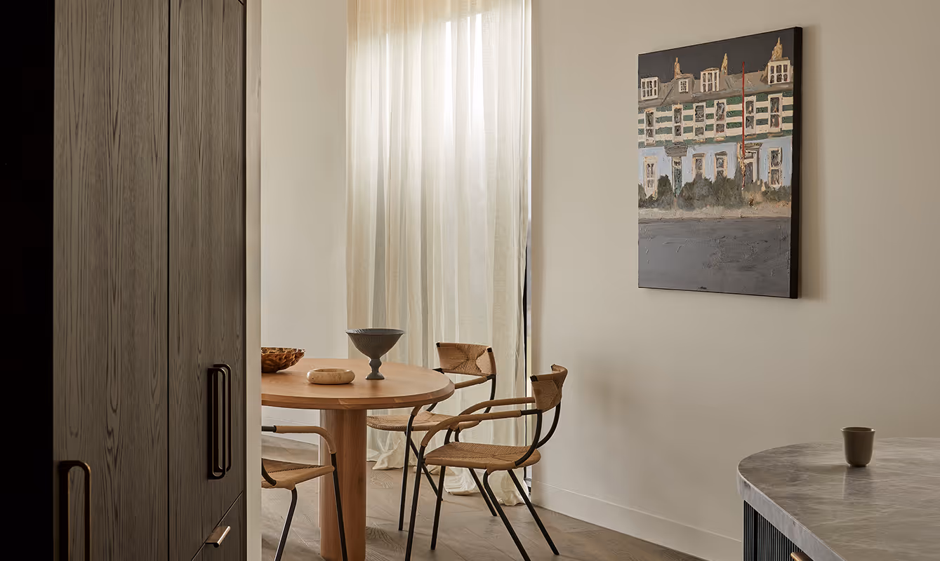 Dining table with cabinet on the side and a hanging picture on the wall.