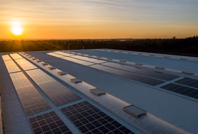 Rooftop solar panel array at sunset on an industrial building