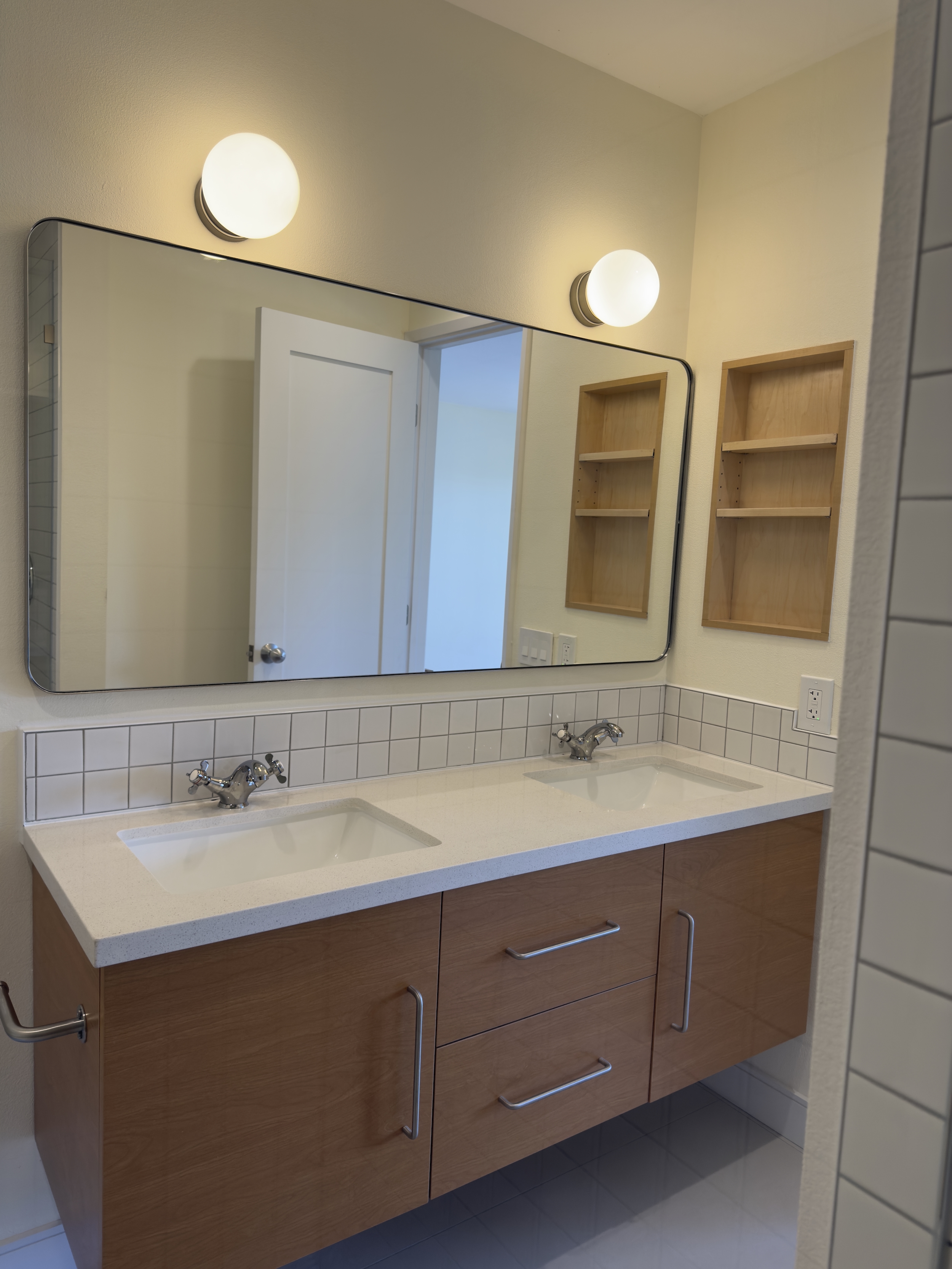 Bathroom remodel with floating double vanity, custom wood vanity cabinet, white countertop, mirror, wall lighting, and tile detail.