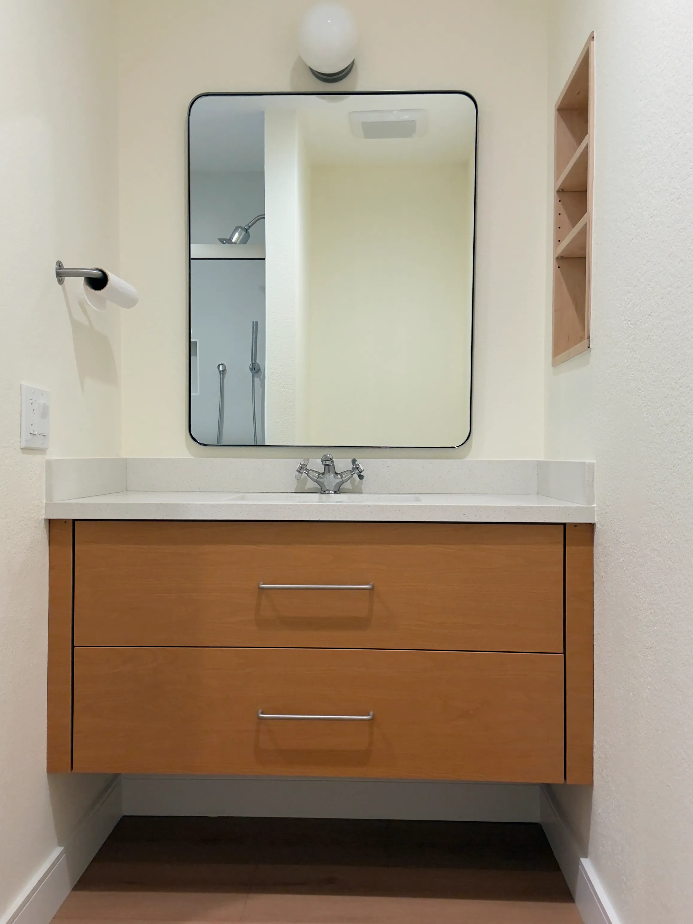 Bathroom remodel with floating single vanity, custom wood vanity cabinet, white countertop, mirror, and wall lighting.