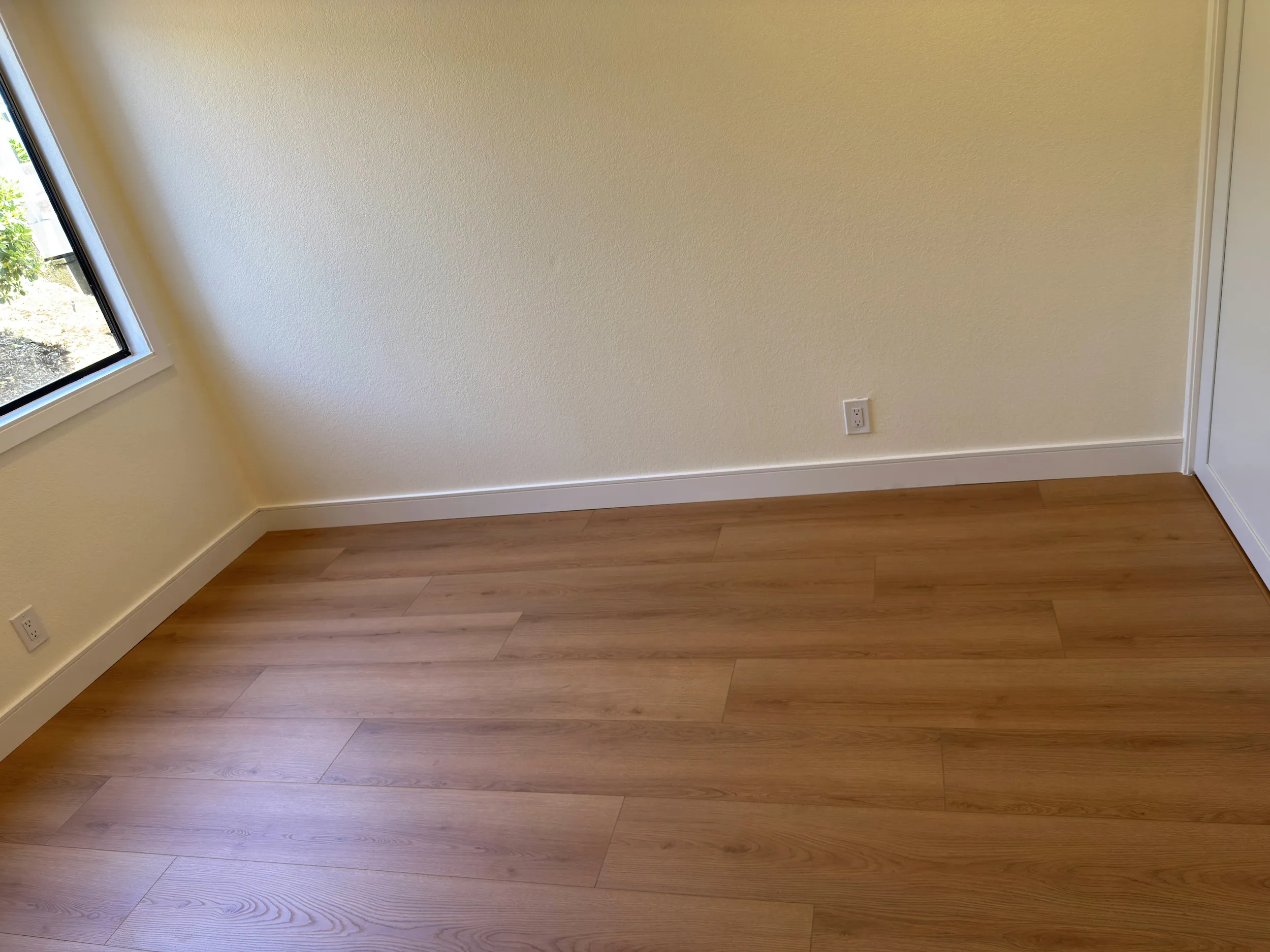 Finished interior flooring with wood-look planks, white baseboards, painted walls, and clean floor transitions.