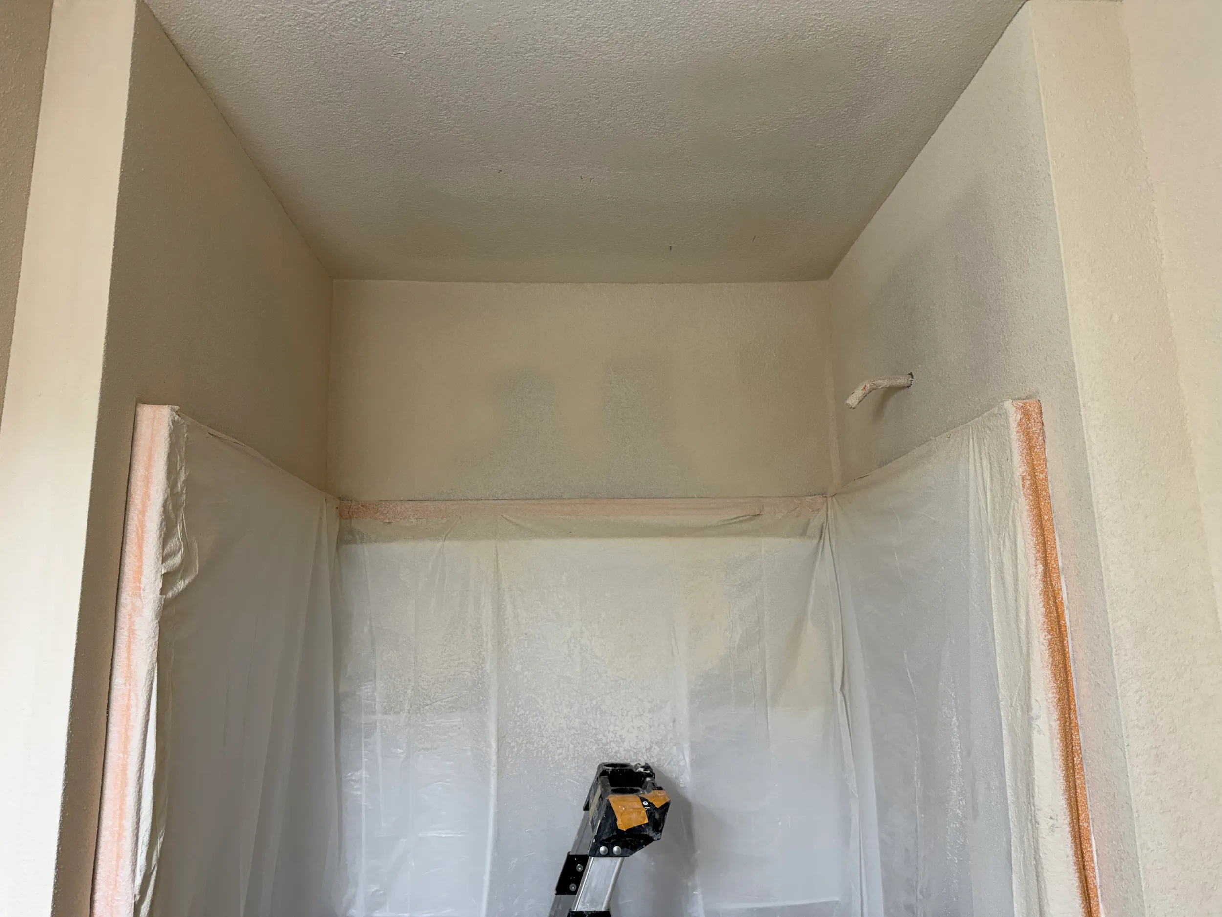 Wall texture being applied in a bathroom area to match the existing rough finish before final painting.
