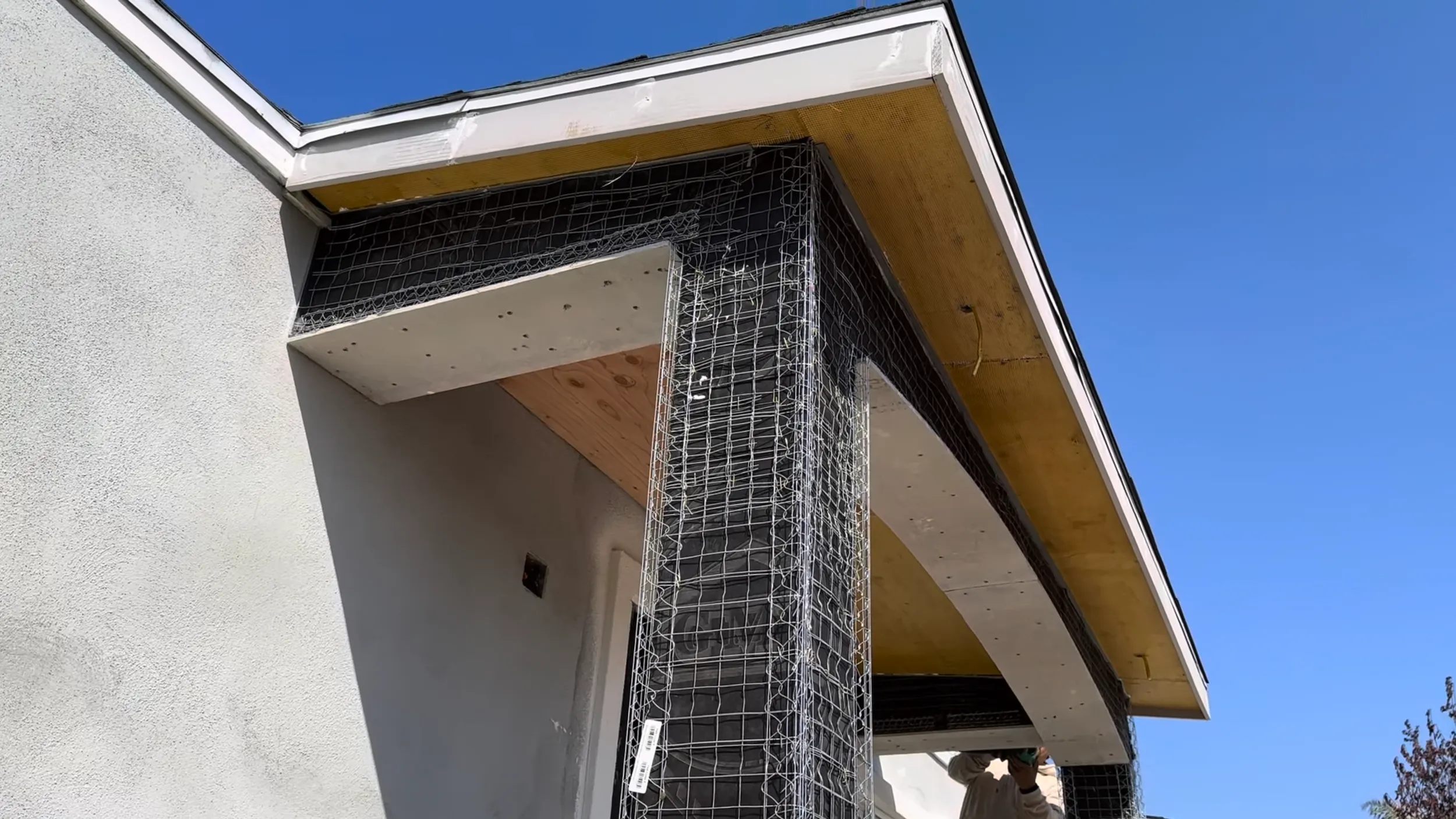 Stucco portico addition in progress at the front entry of a home.