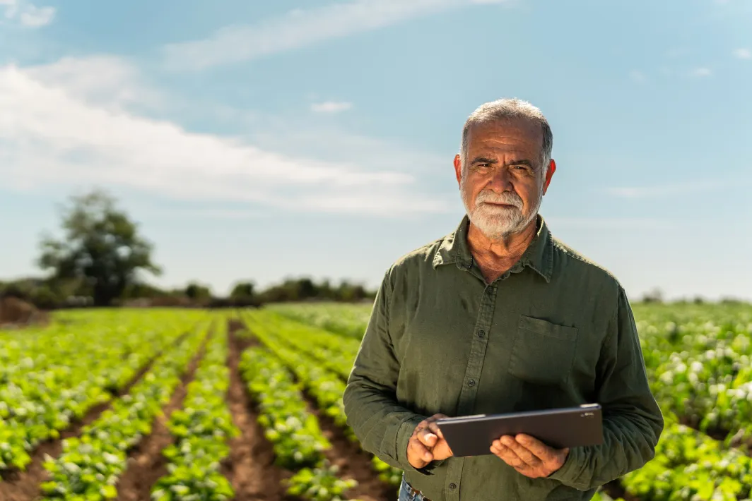 Man holding a tablet standing in a farm field