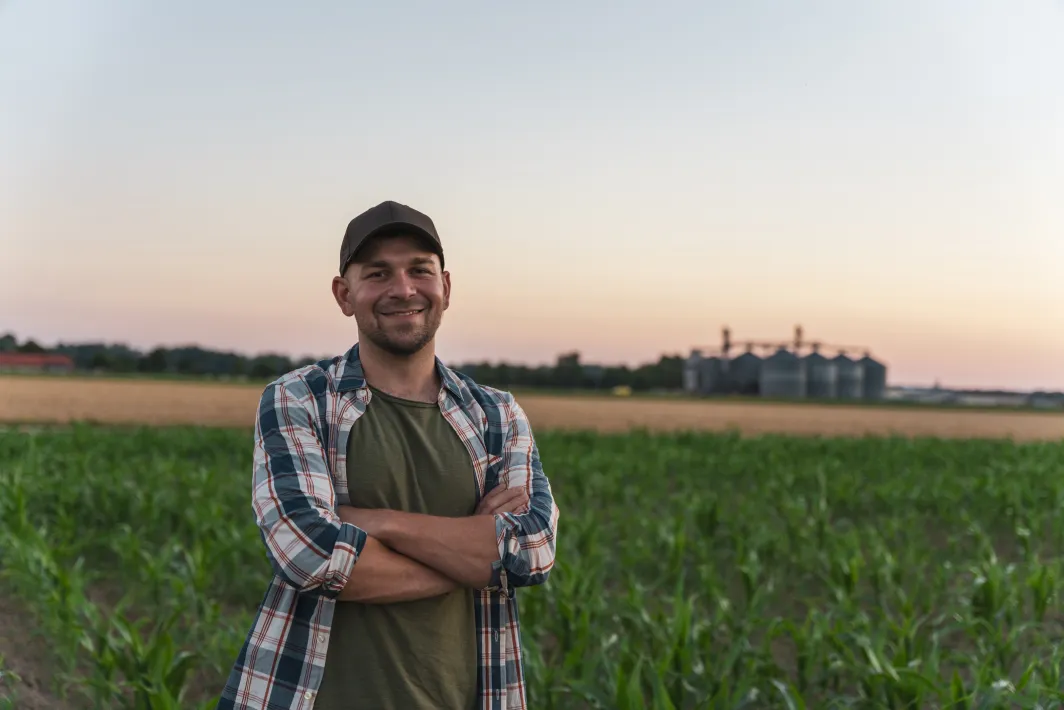 Smiling man with his arms crossed standing in a farm field