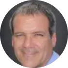 Middle-aged man smiling against a dark background.