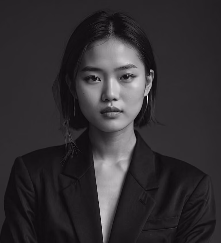 Black and white portrait of a young woman with short hair wearing a dark blazer and hoop earrings against a plain background.