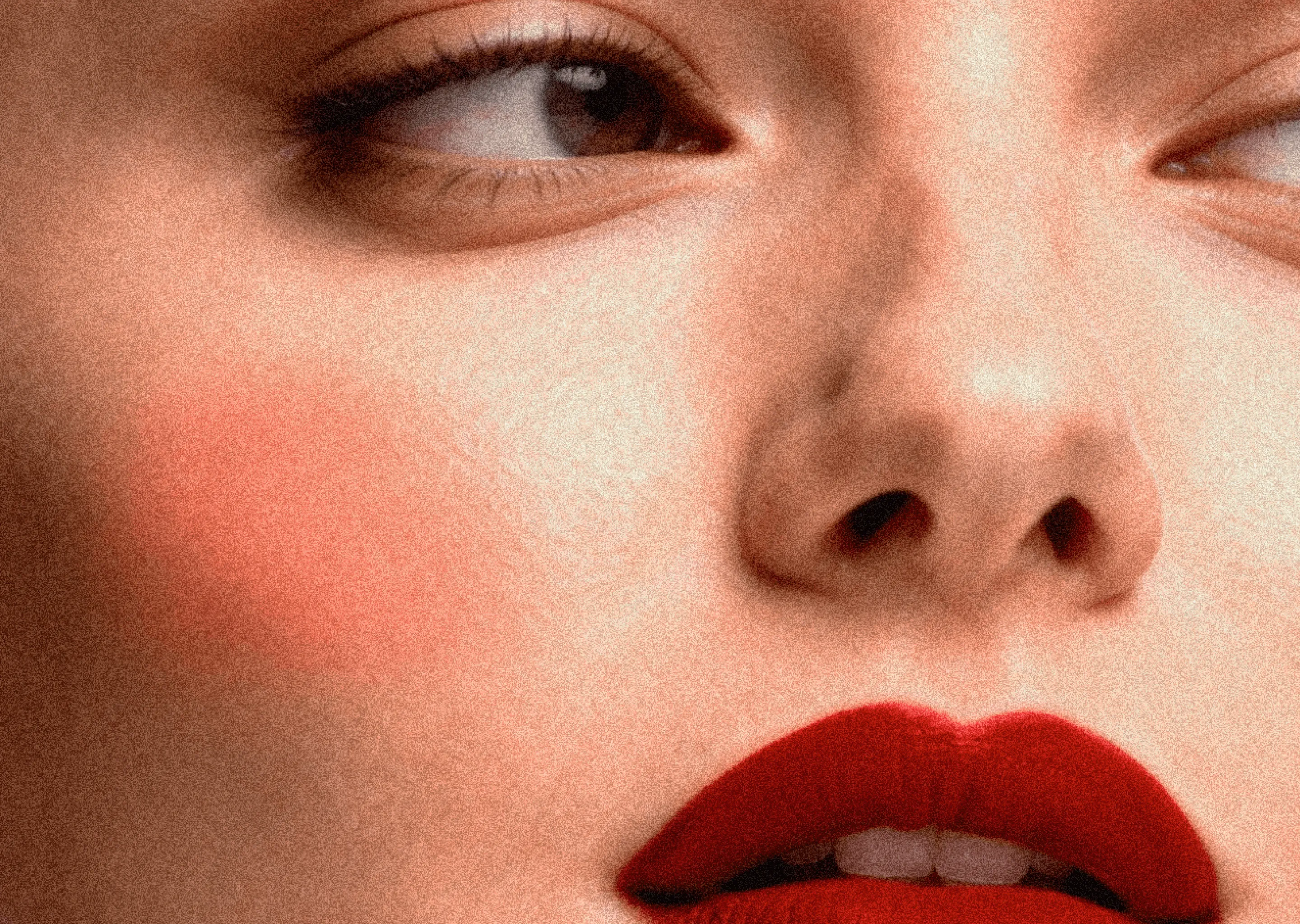 Close-up of a face with red lipstick, rosy cheeks, and eyes looking sideways.