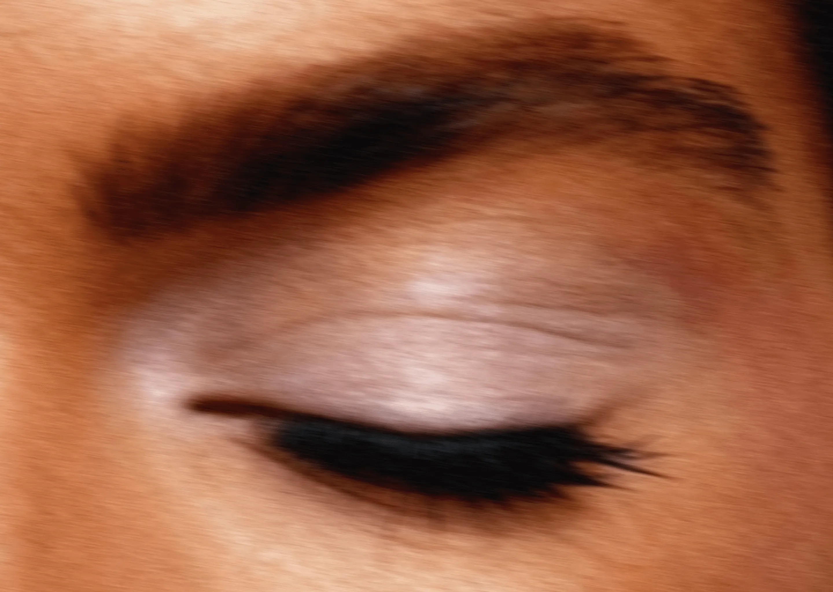 Close-up of a closed eye with well-defined eyebrow and black eyeliner.