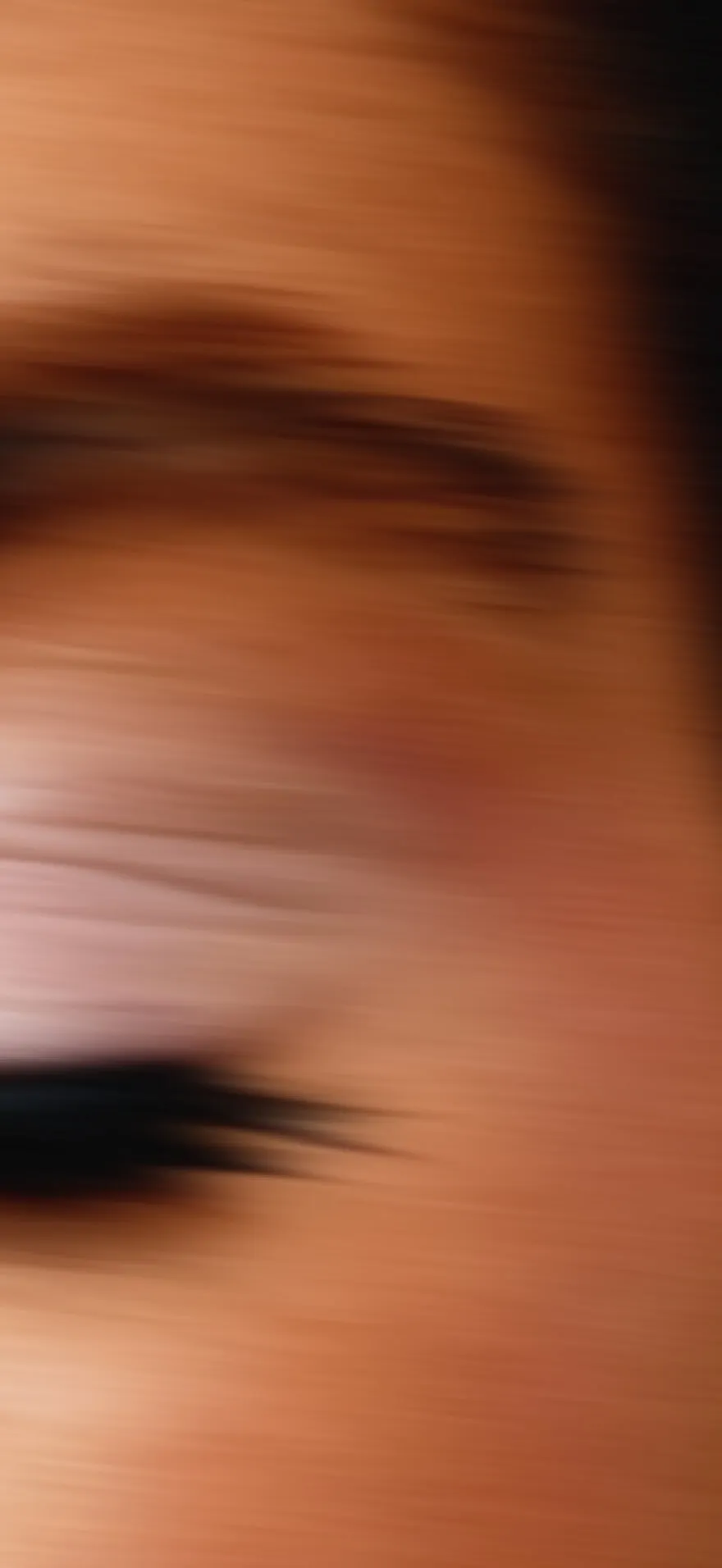 Close-up of a person's closed eye with long eyelashes and blurred skin surface.