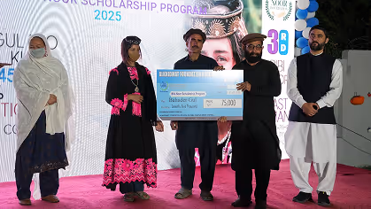 Five people standing on stage holding a large award check for 75,000, with a backdrop showing scholarship program details.