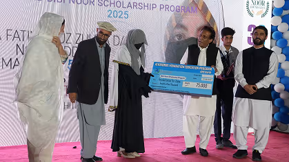 Group of people on stage during Noor Scholarship Program 2025 ceremony, holding a large scholarship cheque.