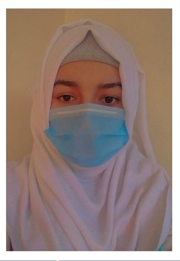 Person wearing a white hijab and a blue surgical mask covering nose and mouth.