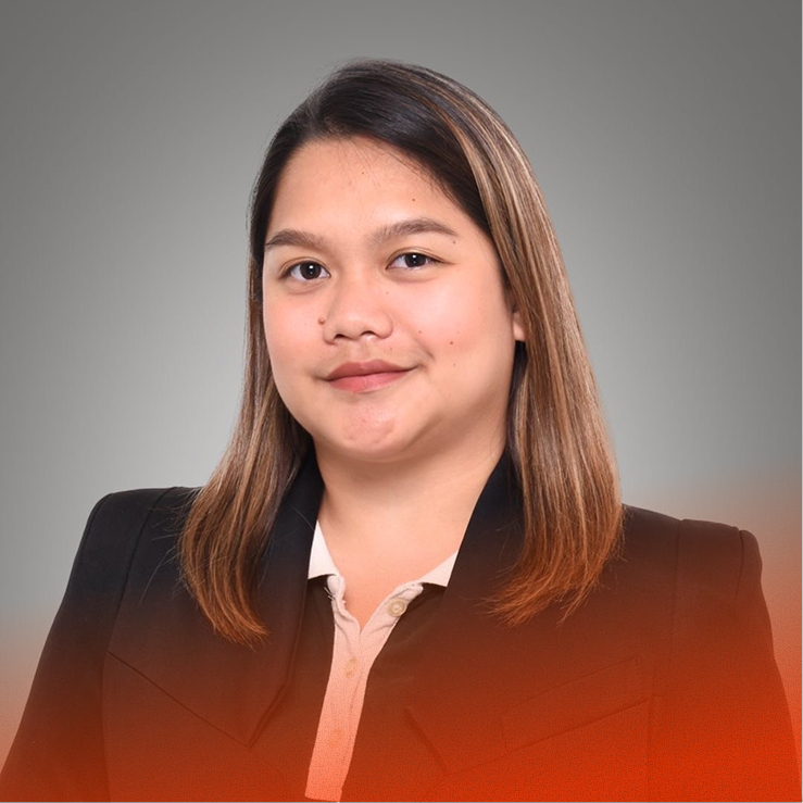 Woman poses, smiling slightly, wearing a blazer in a studio portrait