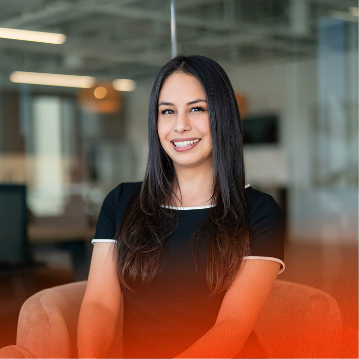 Young woman smiling, seated in an office chair against a glass partition