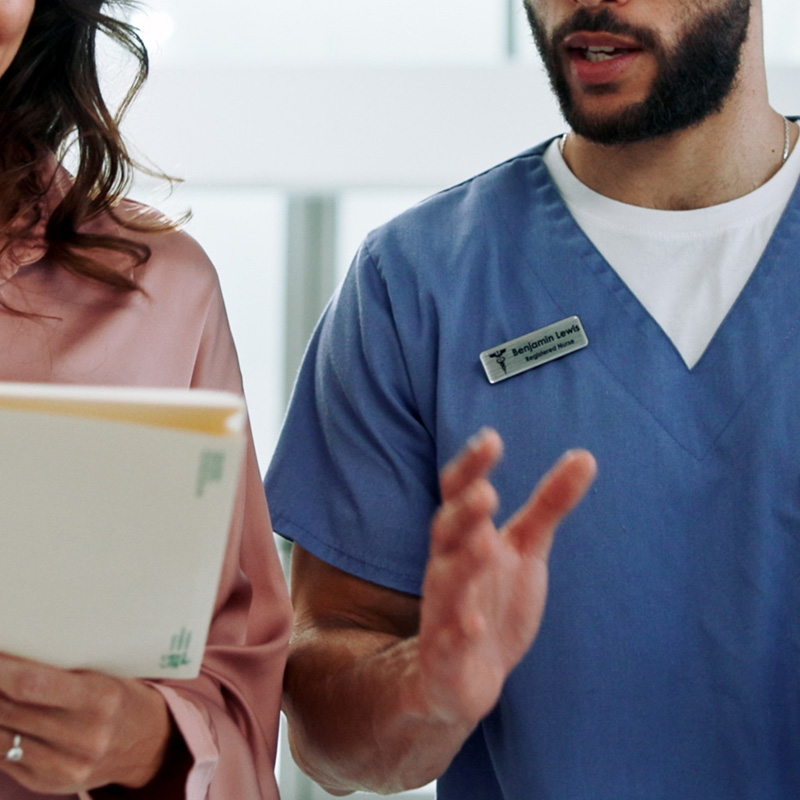 Nurse gesturing while talking beside colleague holding patient files