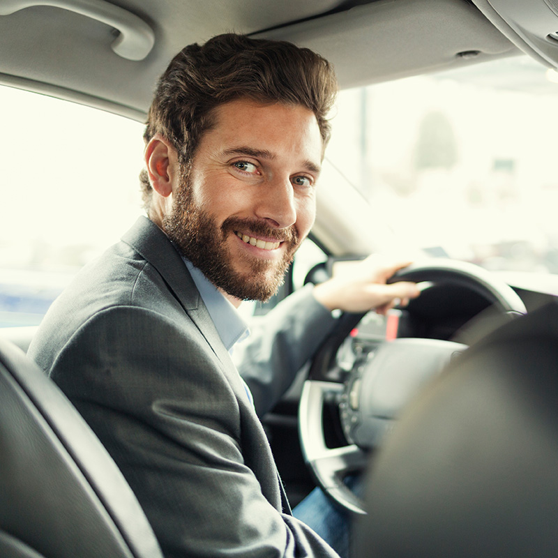 Man smiling while driving a car in business attire